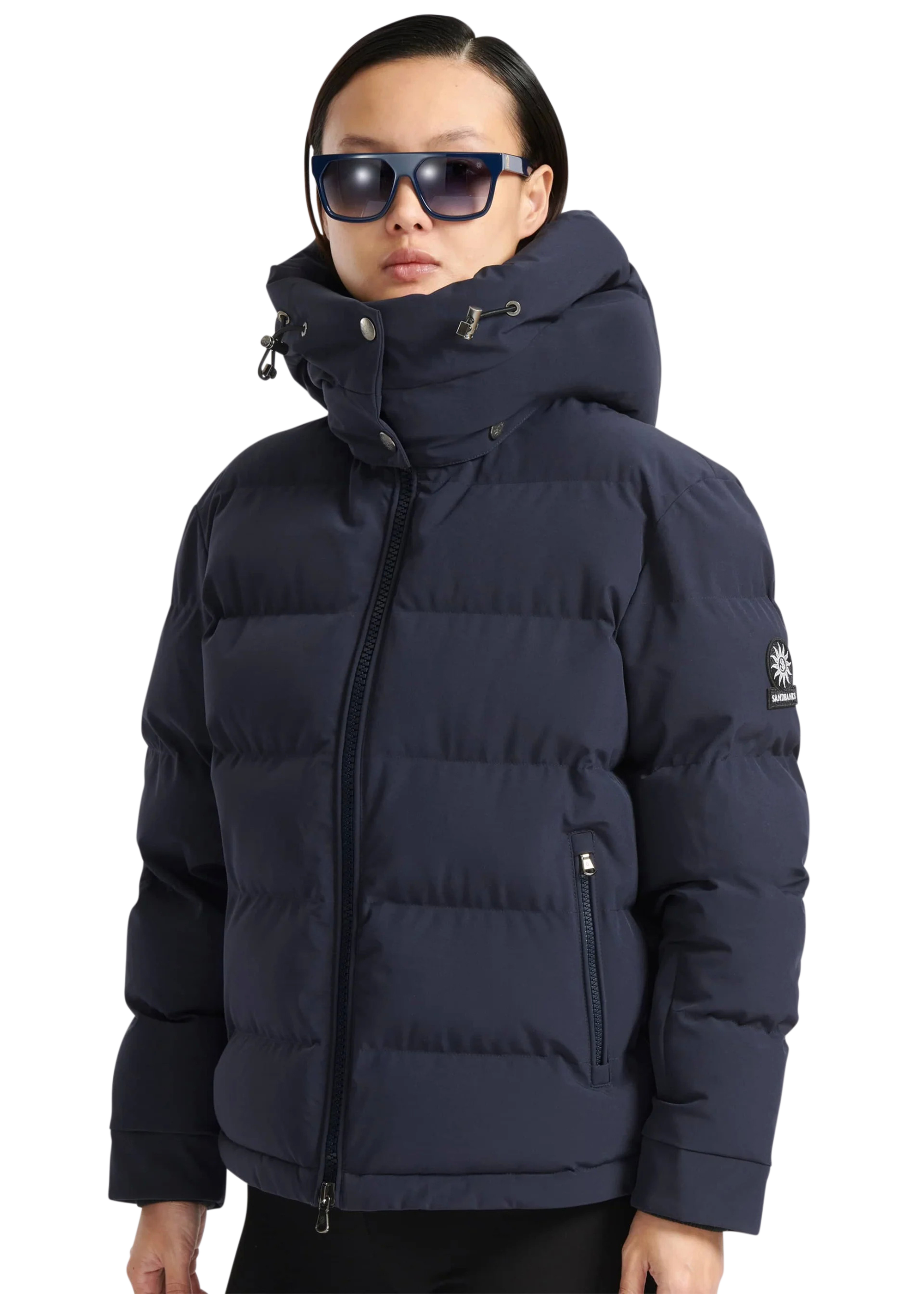 Person wearing a navy blue puffer jacket with a brand logo on a white background