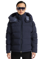 Person wearing a navy blue puffer jacket with a hood on a white background