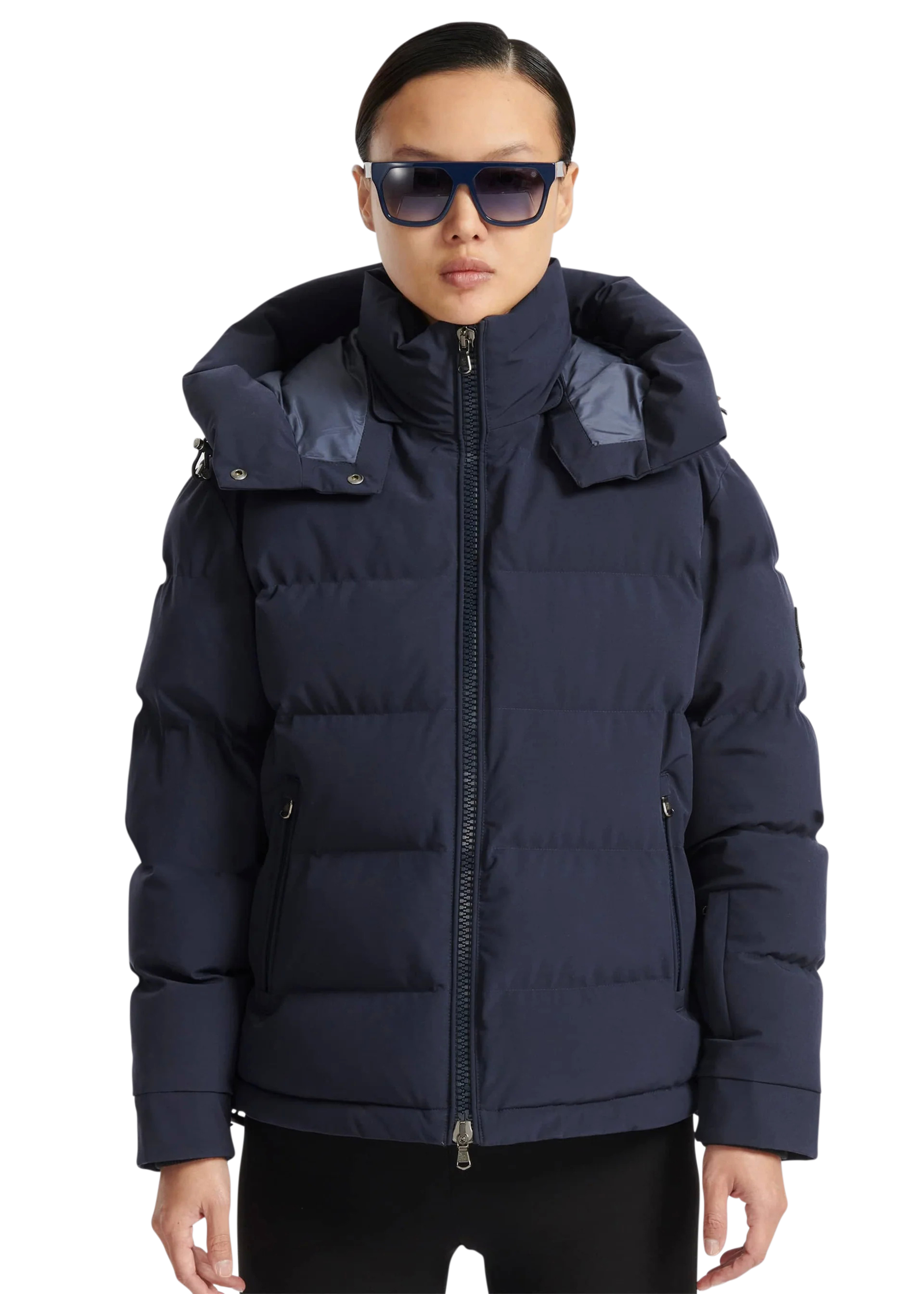 Person wearing a navy blue puffer jacket with a hood on a white background