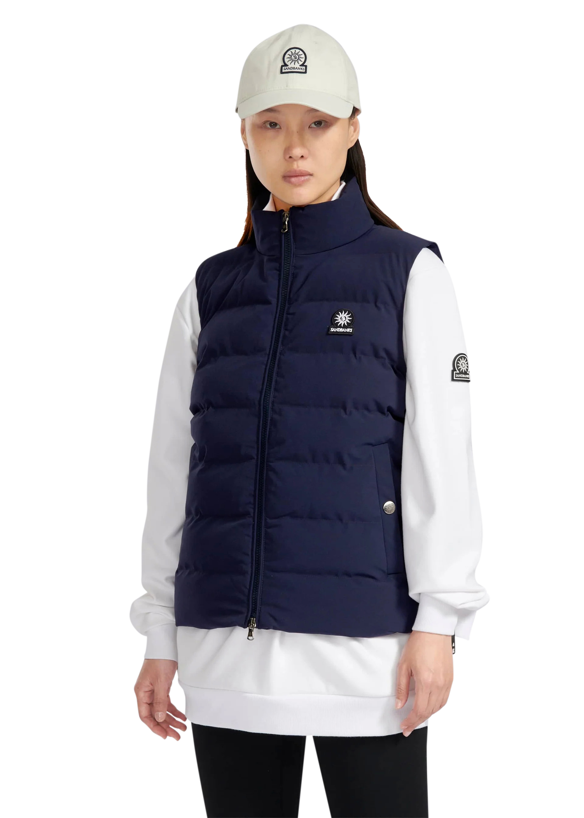 Person wearing a navy puffer vest over a white shirt with a visible brand logo on a white background