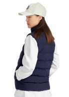 Person wearing a navy puffer vest over a white shirt with a beige cap on a white background