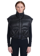 Woman wearing a black puffer vest with a brand logo on a white background