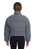 Person wearing a gray quilted jacket on a white background