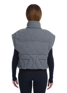Person wearing a gray quilted vest on a white background