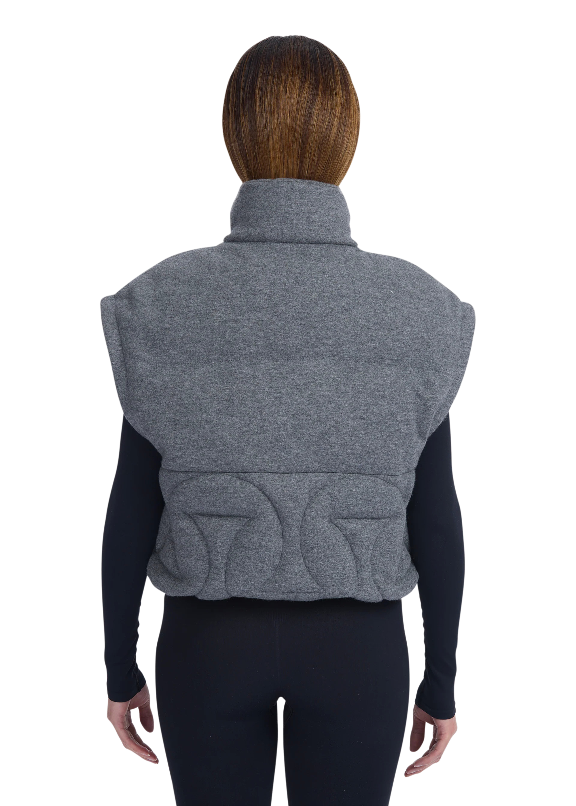 Person wearing a gray quilted vest on a white background