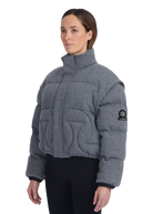 Woman wearing a gray quilted jacket with a brand logo on a white background