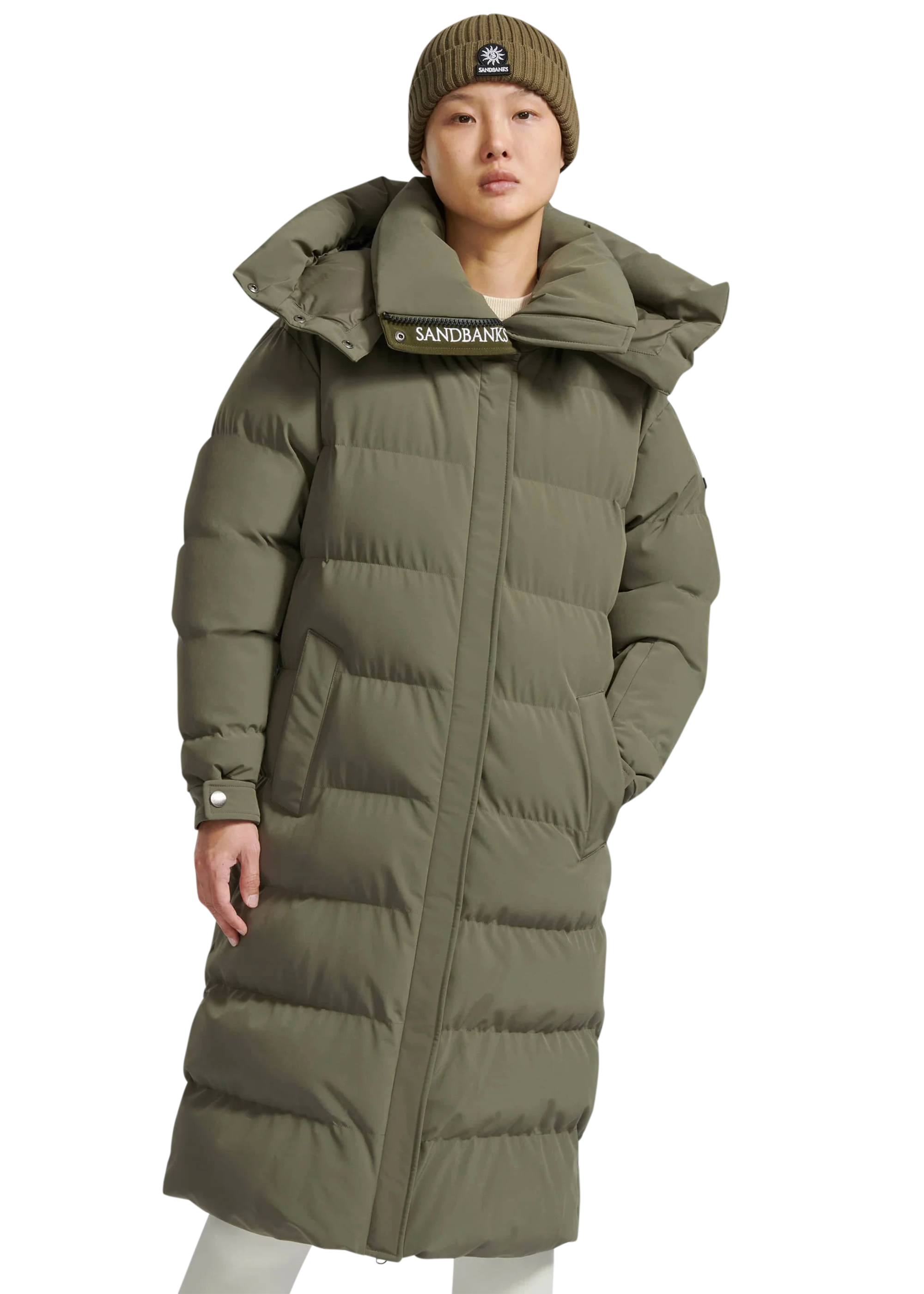 Person wearing a long olive green puffer coat with a hood on a white background