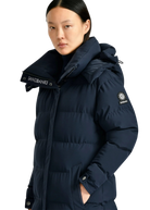 Person wearing a navy blue puffer jacket with brand logos on a white background