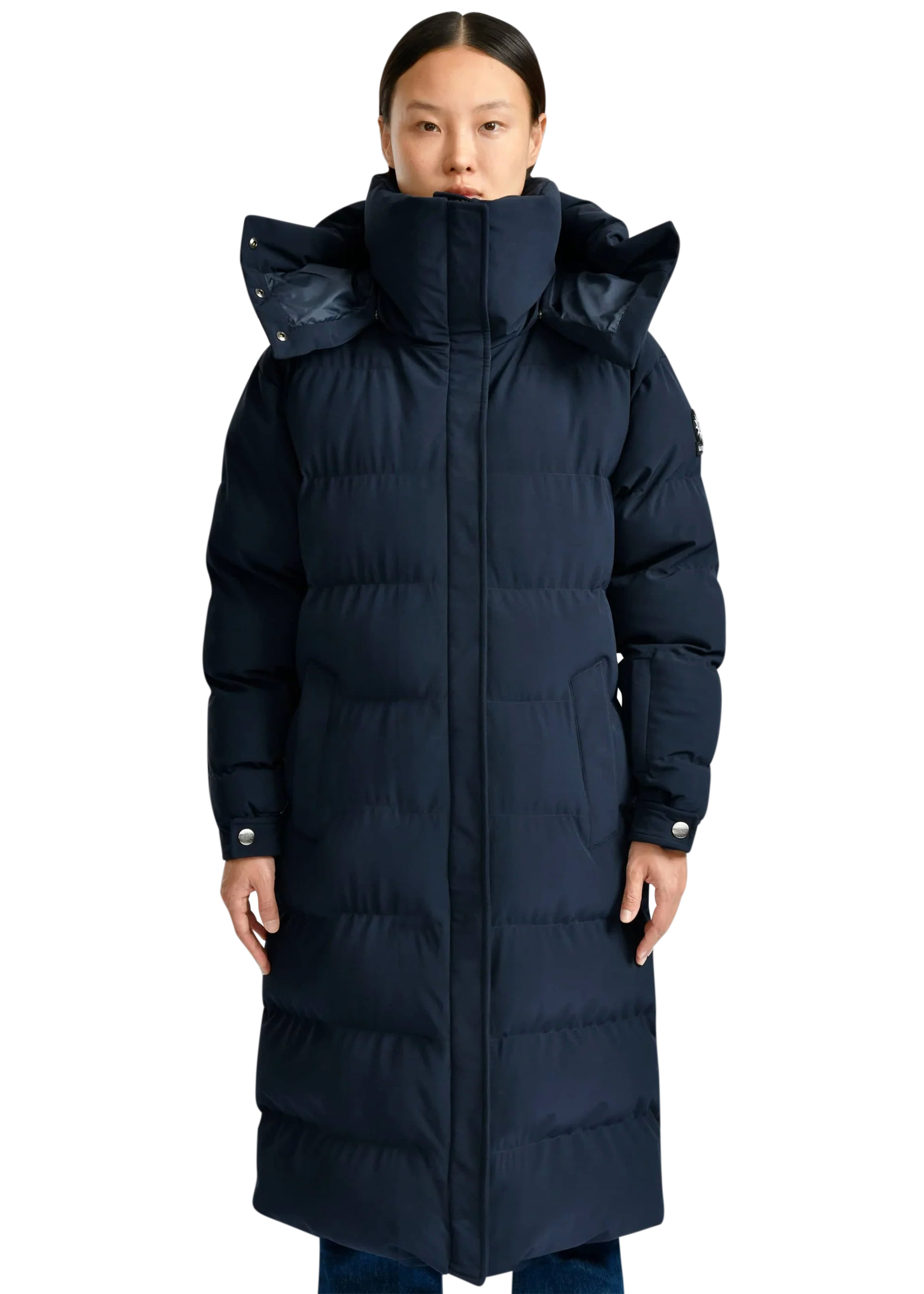 Person wearing a long navy blue puffer coat on a white background