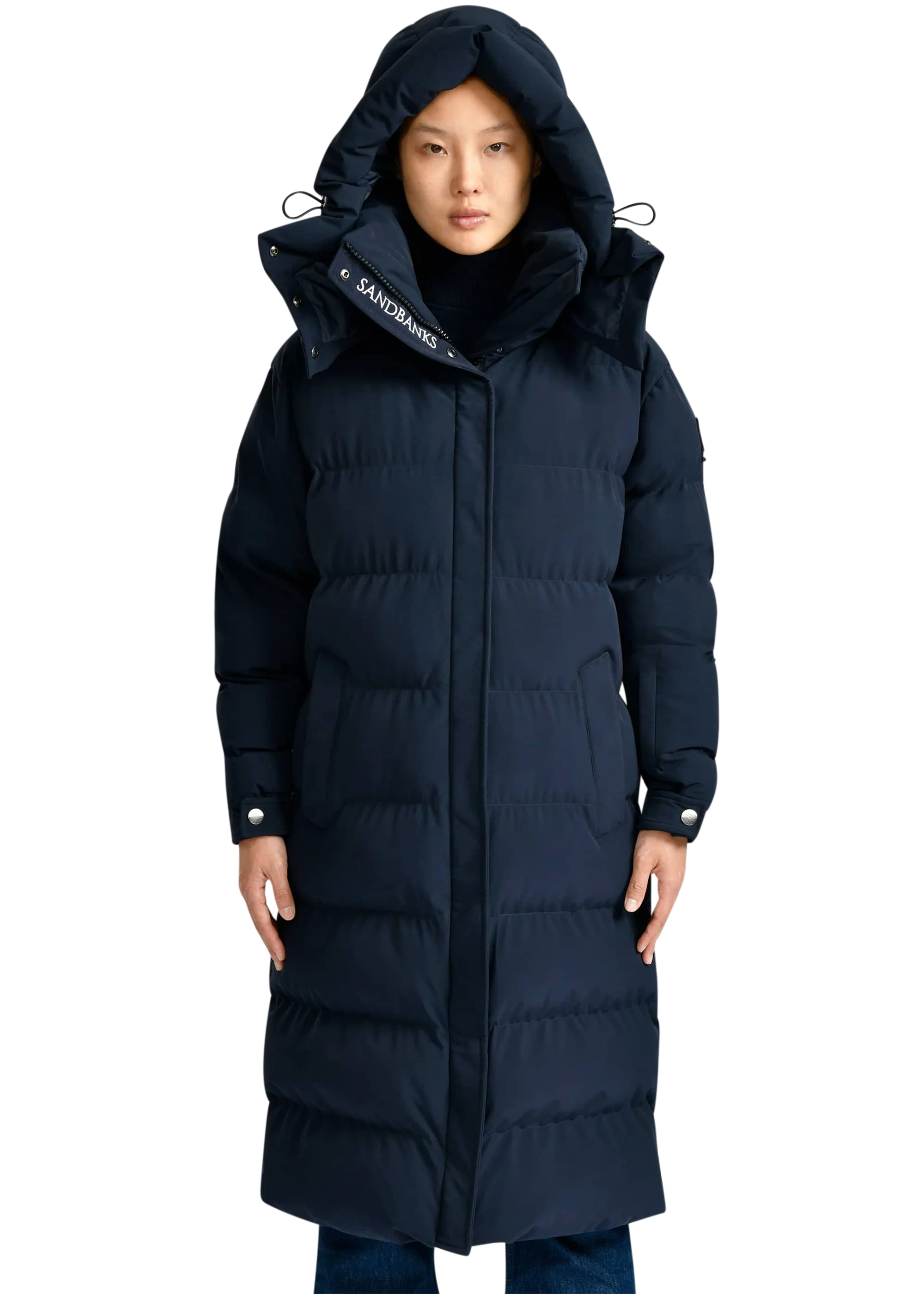 Person wearing a long navy blue puffer coat on a white background
