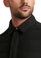 Close-up of a man wearing a black shirt with a tie against a white background