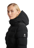 Woman wearing a black puffer jacket with a brand logo on a white background